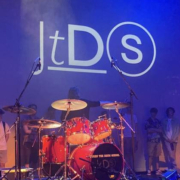 John the Drum School logo projected on to backdrop above drum kit