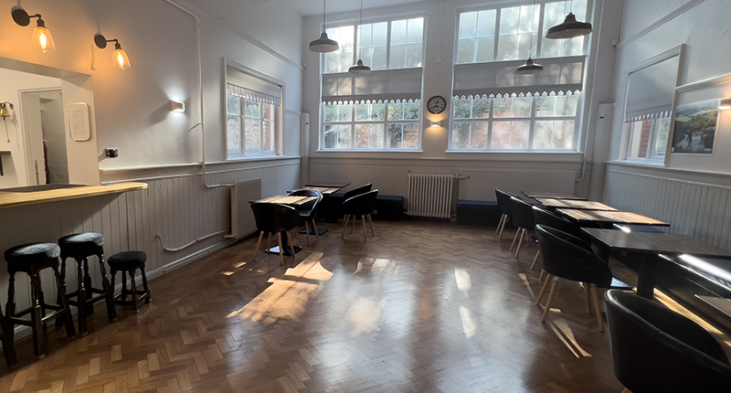 Lounge bar in daytime– with wooden flor, small tables and comfortable seating